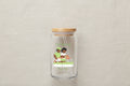 Glass tumbler with a straw lid featuring an illustration of two people gardening and text on a white background.
