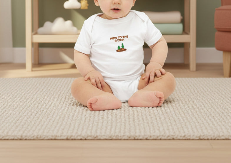 Baby wearing a white onesie with text and graphics on a beige background