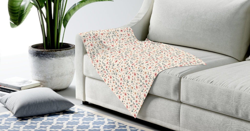 Gray sofa with a patterned blanket, plant, and rug in a living room setting