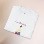 White t-shirt with 'Gardening' text and graphic of a person with a plant on a beige background