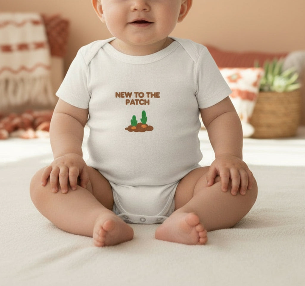 Baby onesie with 'New to the Patch' text on a light green background with party supplies.