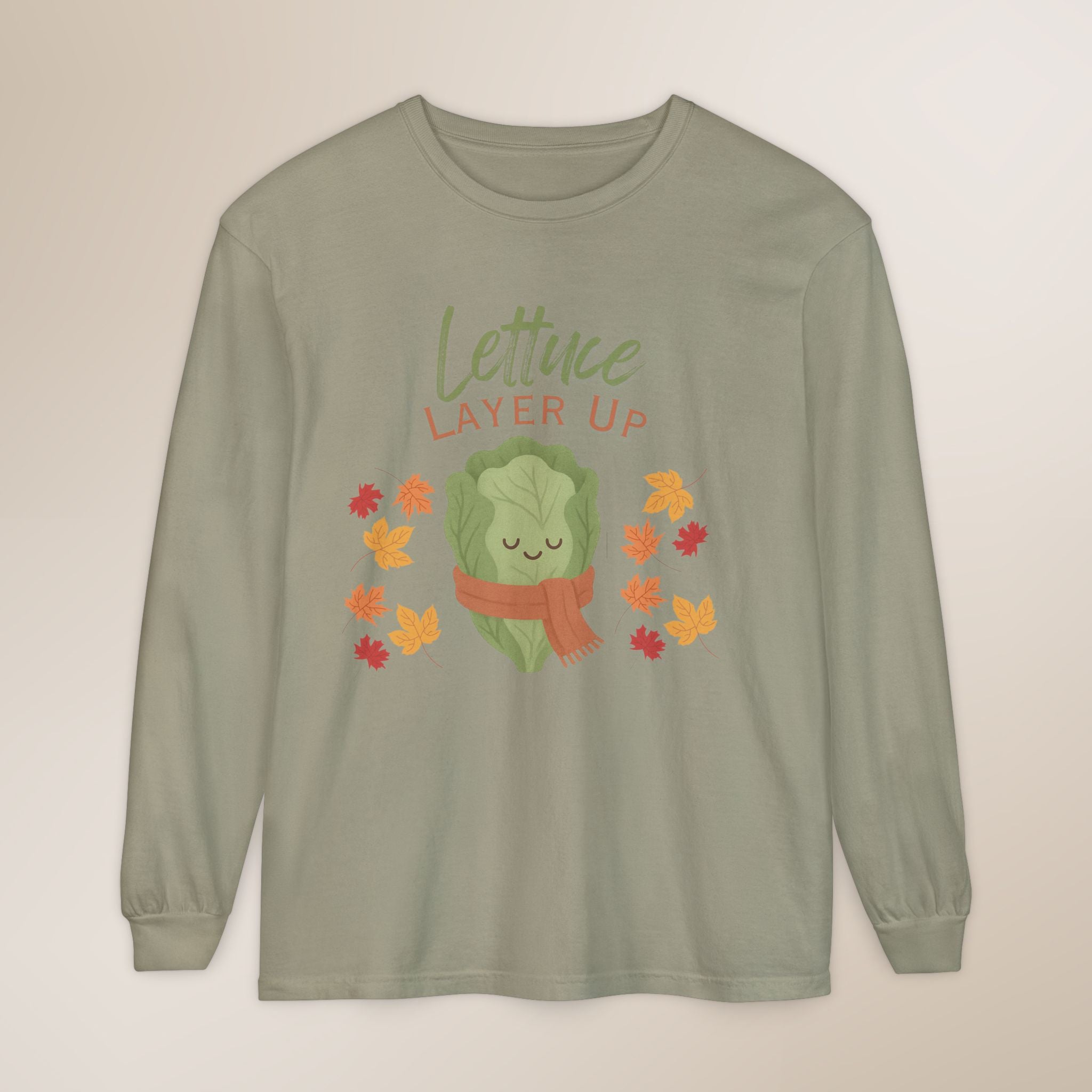 Sage green long-sleeve shirt with a cartoon lettuce character and 'Lettuce Layer Up' text on a beige background
