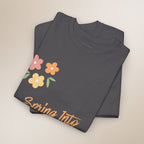 Folded dark gray t-shirt with colorful floral design and 'Spring Into' text on a beige background