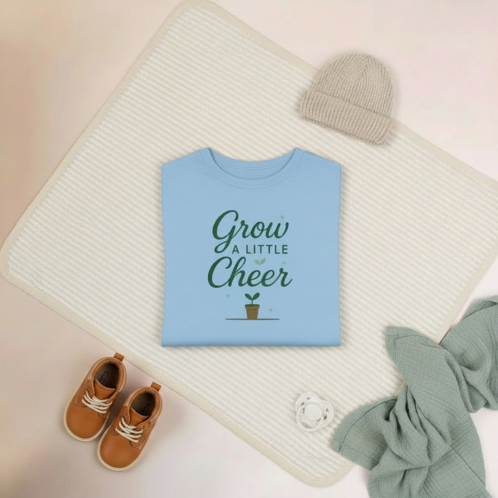 Light blue long-sleeve shirt with 'Grow a Little Cheer' text on a beige background