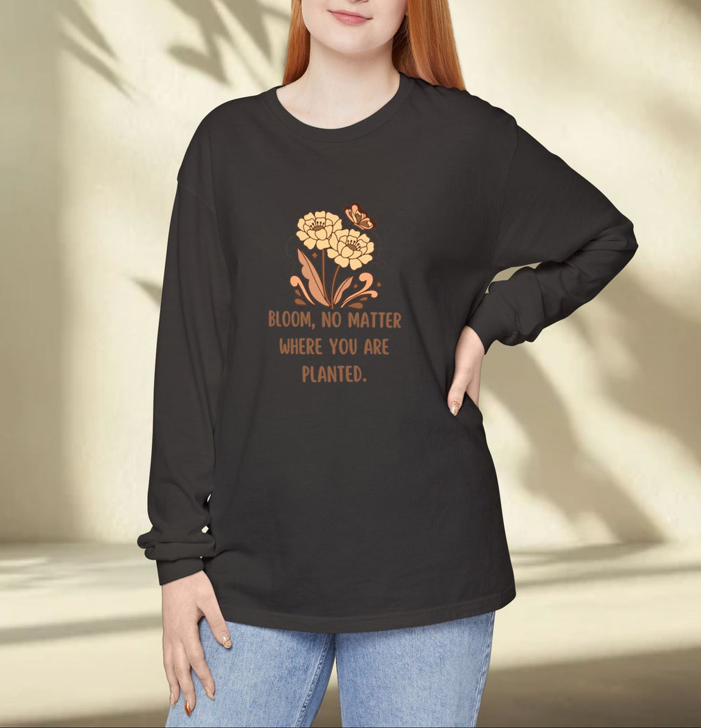 Woman wearing a black long-sleeve shirt with a floral design and text, standing against a neutral background.