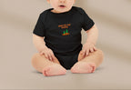 Baby wearing a black onesie with text and graphics on a beige background