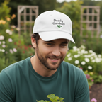 Man wearing a white cap with 'Daddy Gardener' text in a garden setting