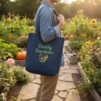 Person holding a navy tote bag with 'Daddy Gardener' text in a garden setting