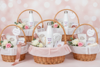 Set of gift baskets with flowers and water bottles on a pink background