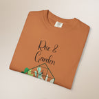 Folded brown t-shirt with 'Rise & Garden' text and plant design on a beige background