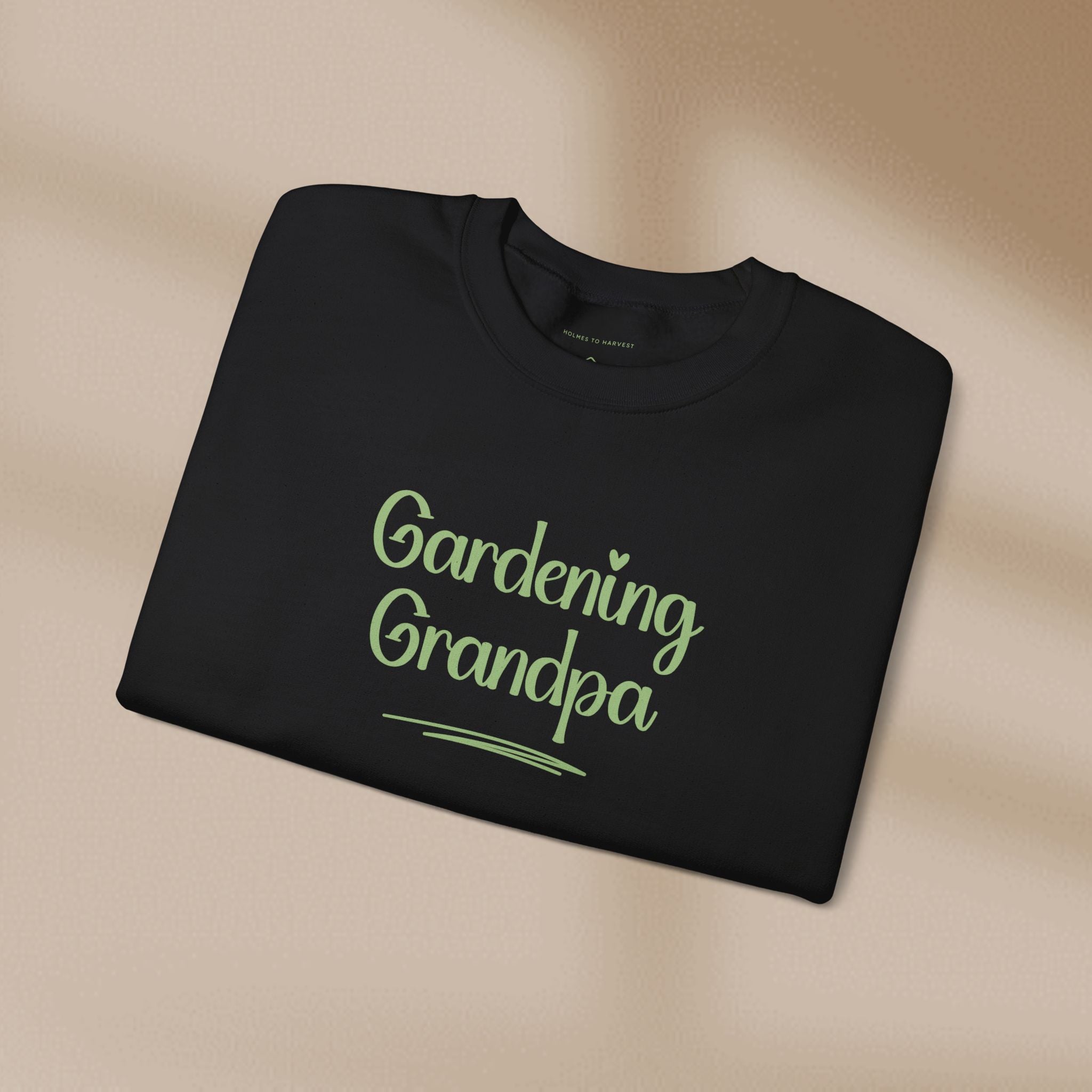 Folded black t-shirt with 'Gardening Grandpa' text on a beige background