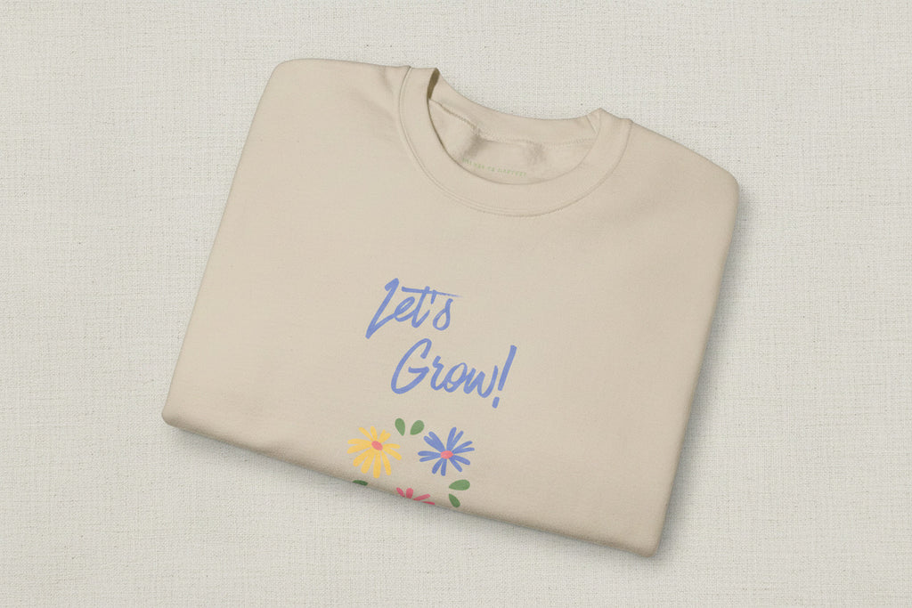 Beige sweatshirt with 'Let's Grow!' text and floral designs on a white background