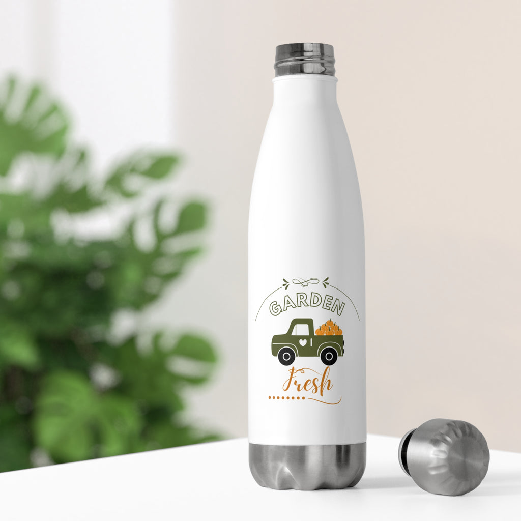 White water bottle with 'Garden Fresh' design on a white surface with greenery in the background