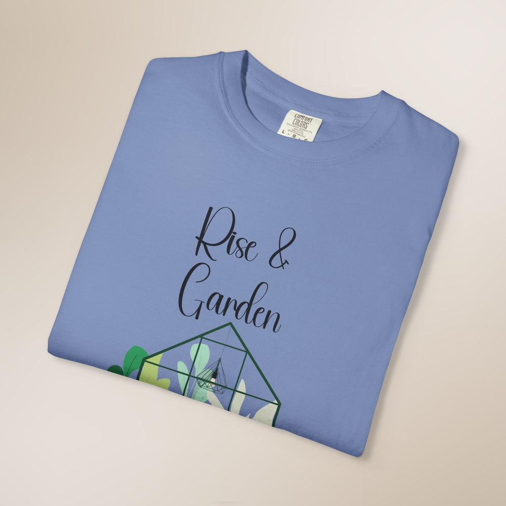 Folded blue t-shirt with 'Rise & Garden' text and green graphic on a beige background