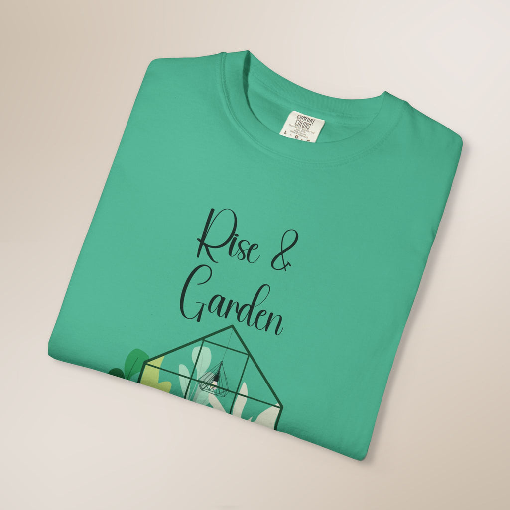 Folded green t-shirt with 'Rise & Garden' text on a beige background