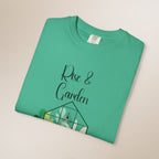 Folded green t-shirt with 'Rise & Garden' text on a beige background