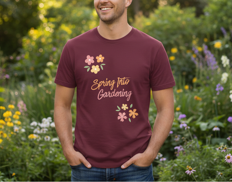 Man wearing a maroon t-shirt with 'Spring Into Gardening' text and floral designs in a garden setting