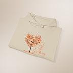 Folded beige hoodie with a tree and 'Fall into Gardening' text on a light background