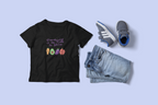 Black t-shirt with colorful graphic and text, denim shorts, and sneakers on a light blue background