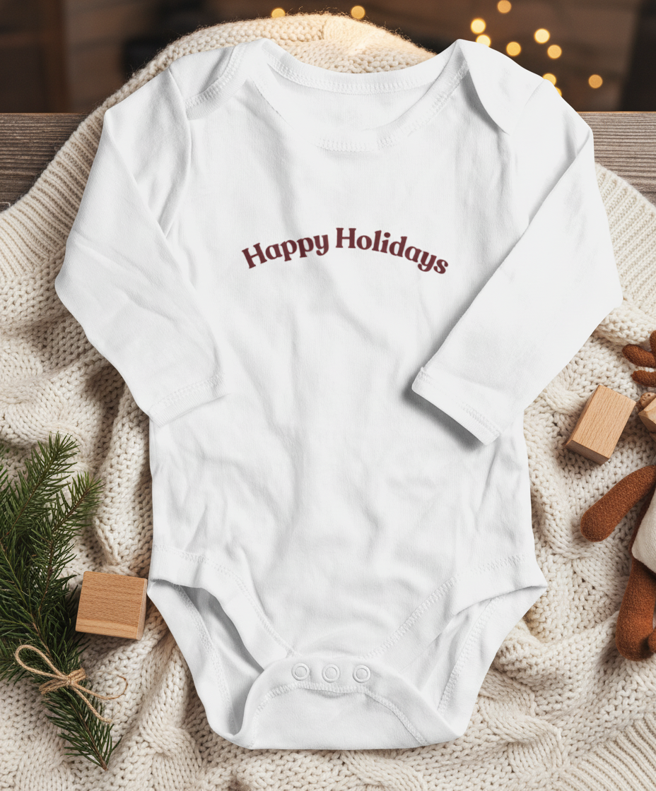 White baby onesie with 'Happy Holidays' text on a textured surface with Christmas decorations.