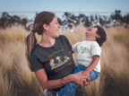 Woman holding a child in a field with a clear sky