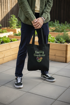 Person holding a black tote bag with 'Daddy Gardener' text in an outdoor setting.