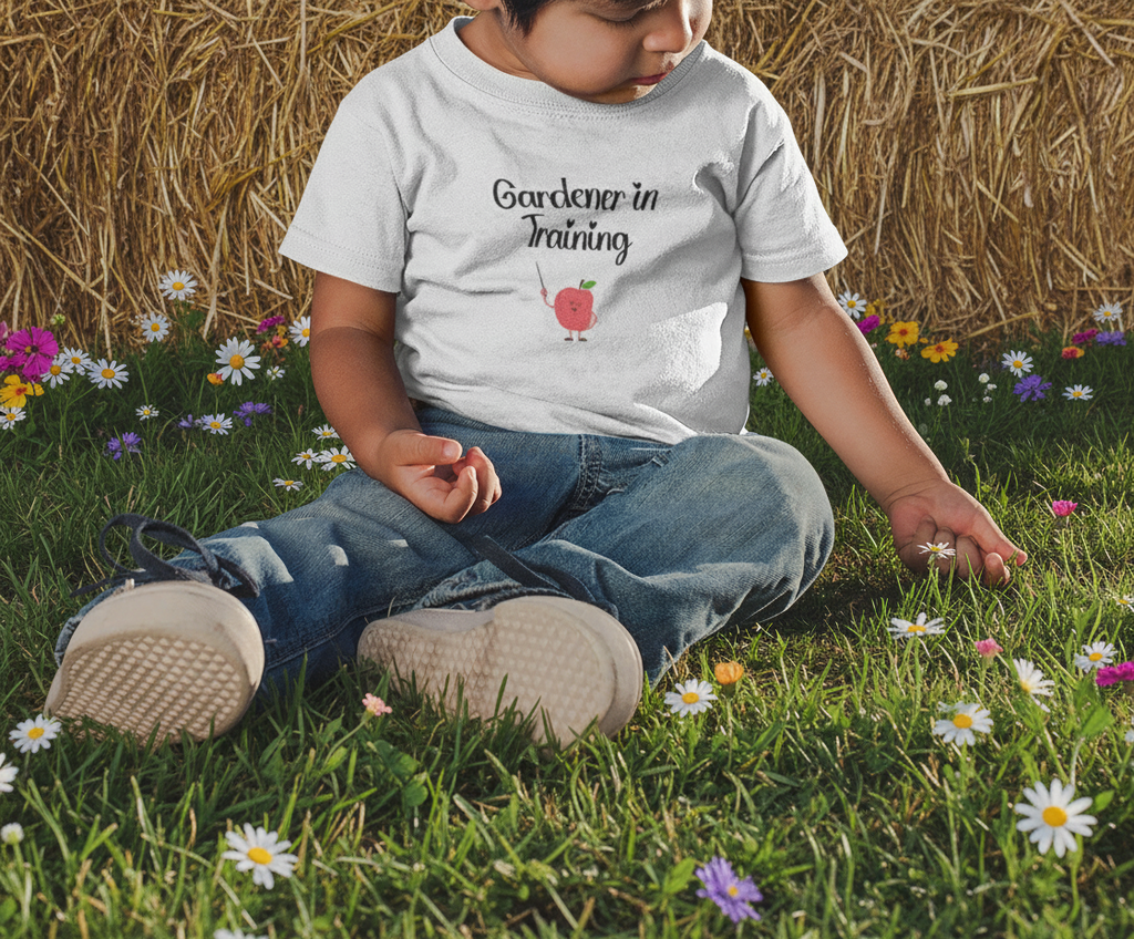 Child sitting in grass wearing a shirt with text and graphics