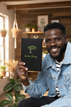Man holding a black book titled 'Garden Strong' in a home setting with plants.