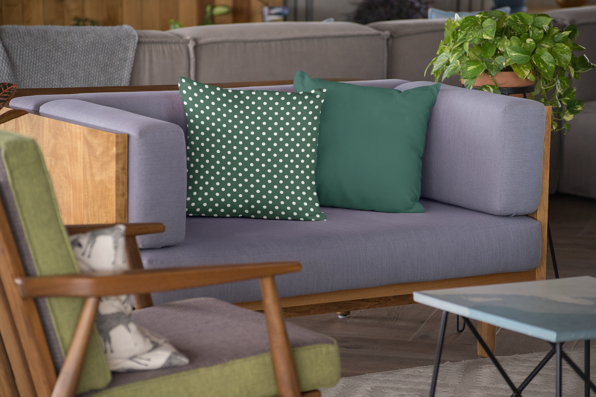 Gray sofa with green and white polka dot cushions, wooden armchair, and small table in a living room setting.