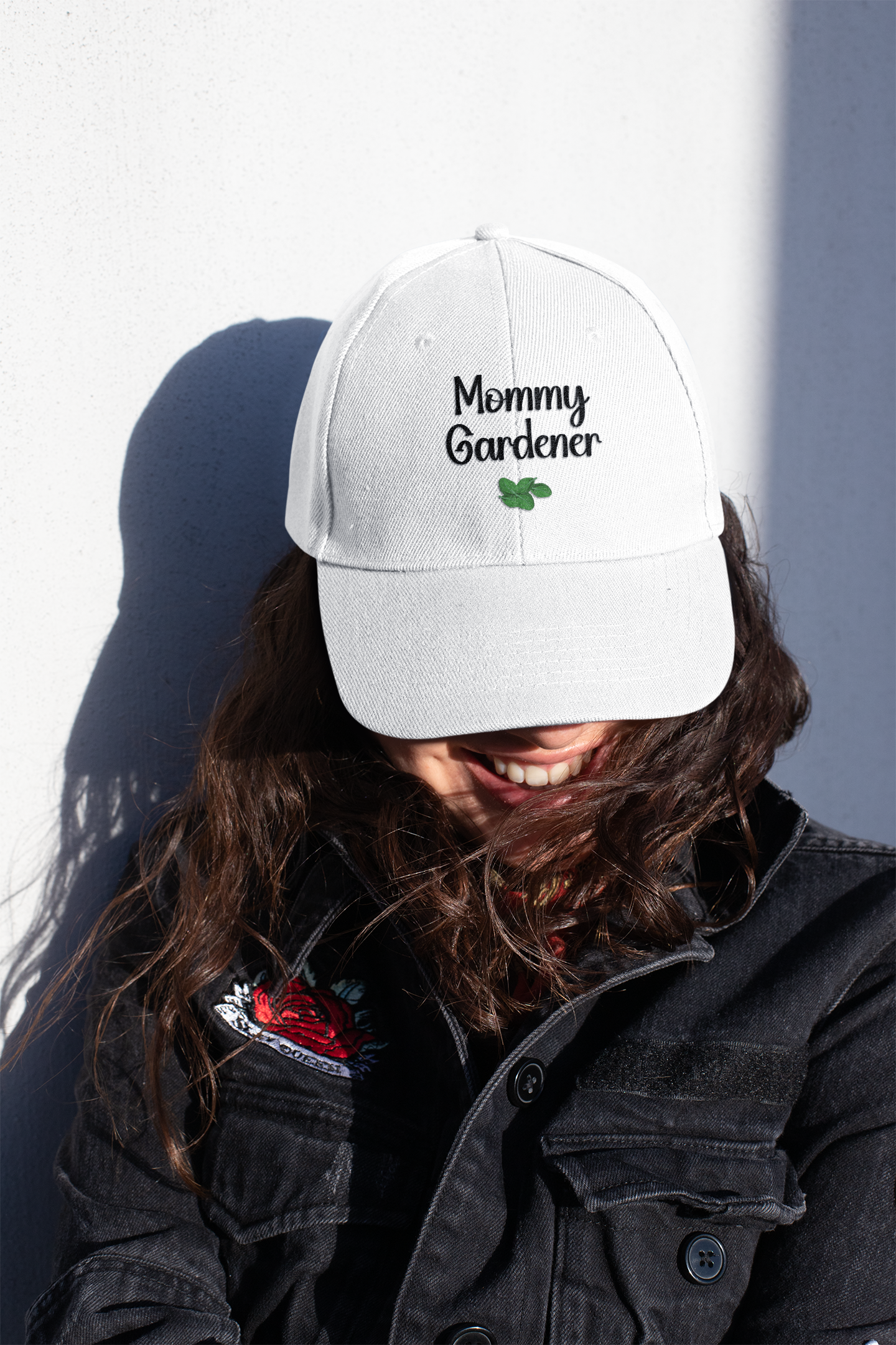 Person wearing a white cap with 'Mommy Gardener' text against a plain background