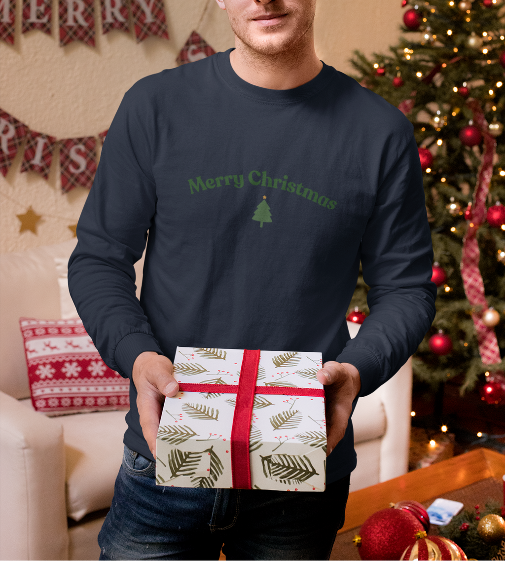 Man holding a gift box in front of a decorated Christmas tree and 'Merry Christmas' banner.