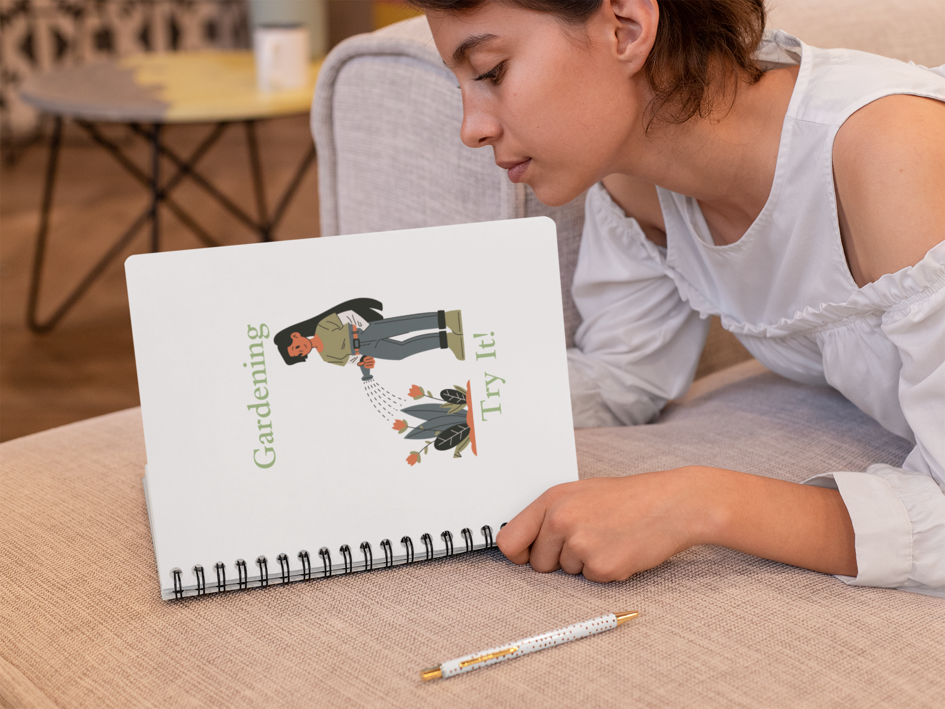 Woman reading a notebook with gardening illustration on a couch