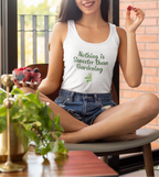 Woman wearing a white tank top with 'Nothing is Sweeter than Gardening' text, sitting indoors.