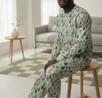 Person wearing a patterned pajama set sitting on a stool in a living room.