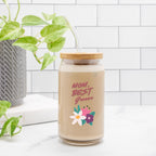 Glass jar with a wooden lid and floral design on a white surface with a plant in the background.