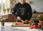 Person in a kitchen wearing a black sweatshirt with 'Gardening is My Therapy' text, cutting vegetables.