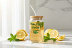 Jar of lemonade with a straw, surrounded by lemons and mint leaves on a light background.