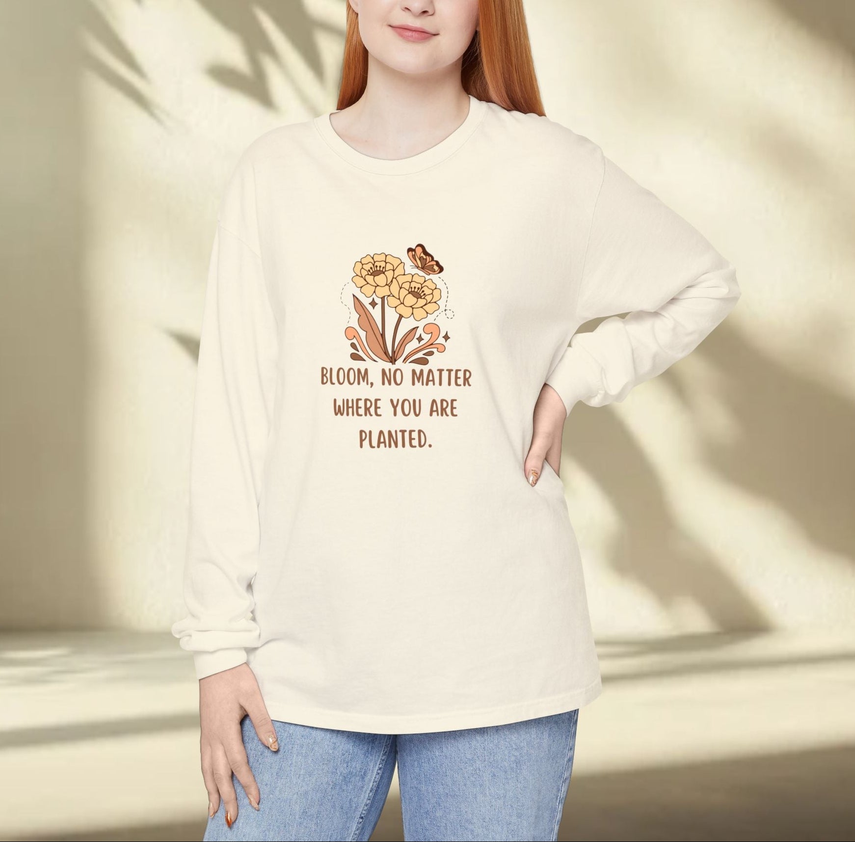 Person wearing a cream-colored sweatshirt with a floral design and text, standing against a neutral background.
