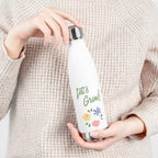 Person holding a white water bottle with 'Let's Grow!' text and floral designs.