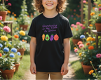 Child wearing a black t-shirt with colorful vegetable graphics and text in a garden setting