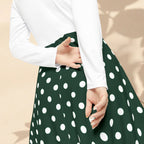 Green polka dot skirt with white long-sleeve top on a beige background