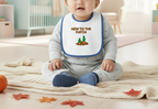 Baby wearing a bib with 'New to the Patch' text and cactus illustration, sitting on a blanket.