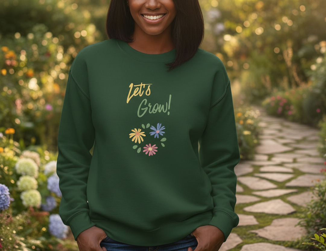 Person wearing a green sweatshirt with 'Let's Grow!' text and floral designs in a garden setting