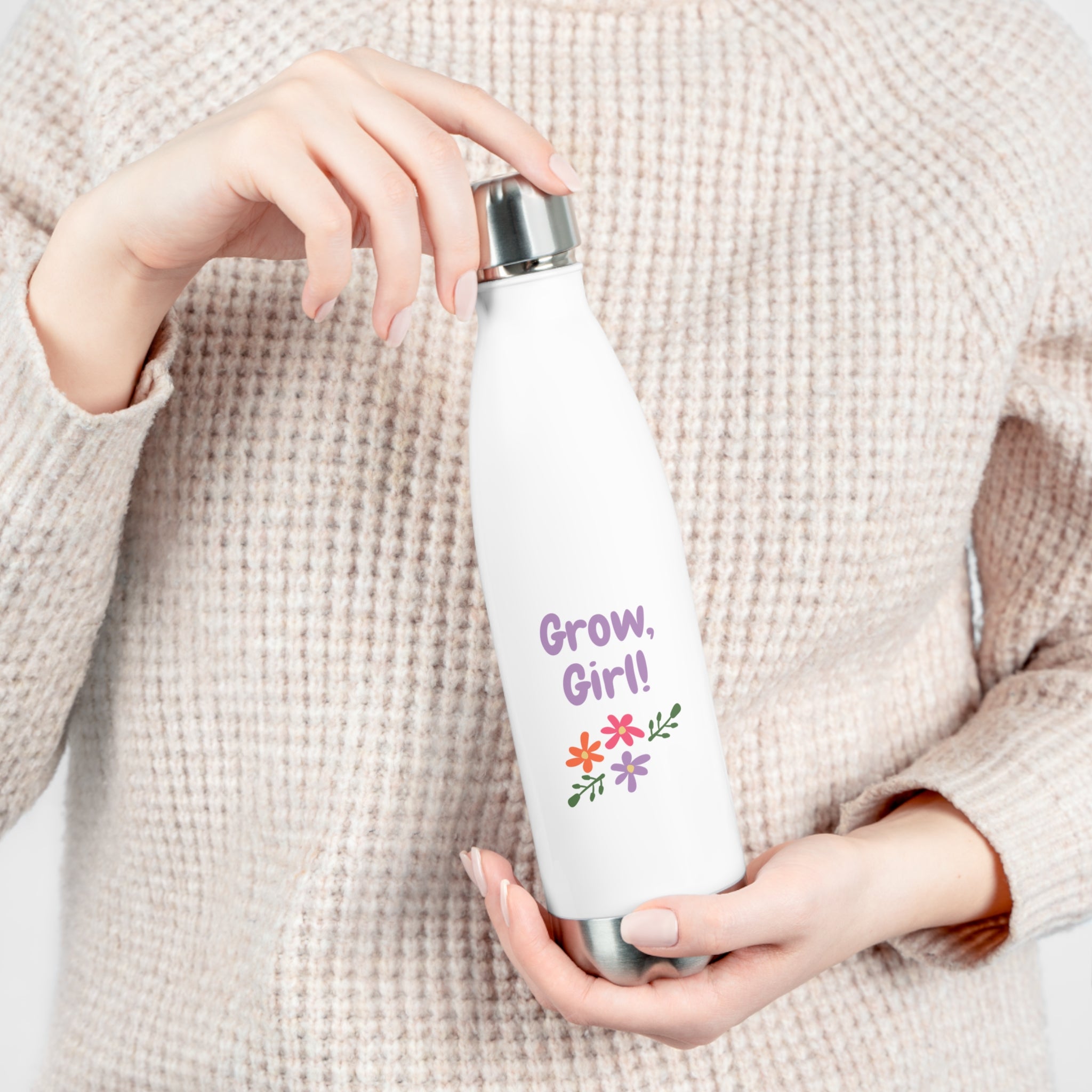 Person holding a white water bottle with 'Grow, Girl!' text and floral design.