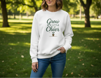 White sweatshirt with 'Grow a Little Cheer' text and plant graphic on a white background