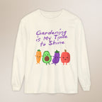 White long-sleeve shirt with cartoon vegetables and text 'Gardening is My Time to Shine' on a beige background