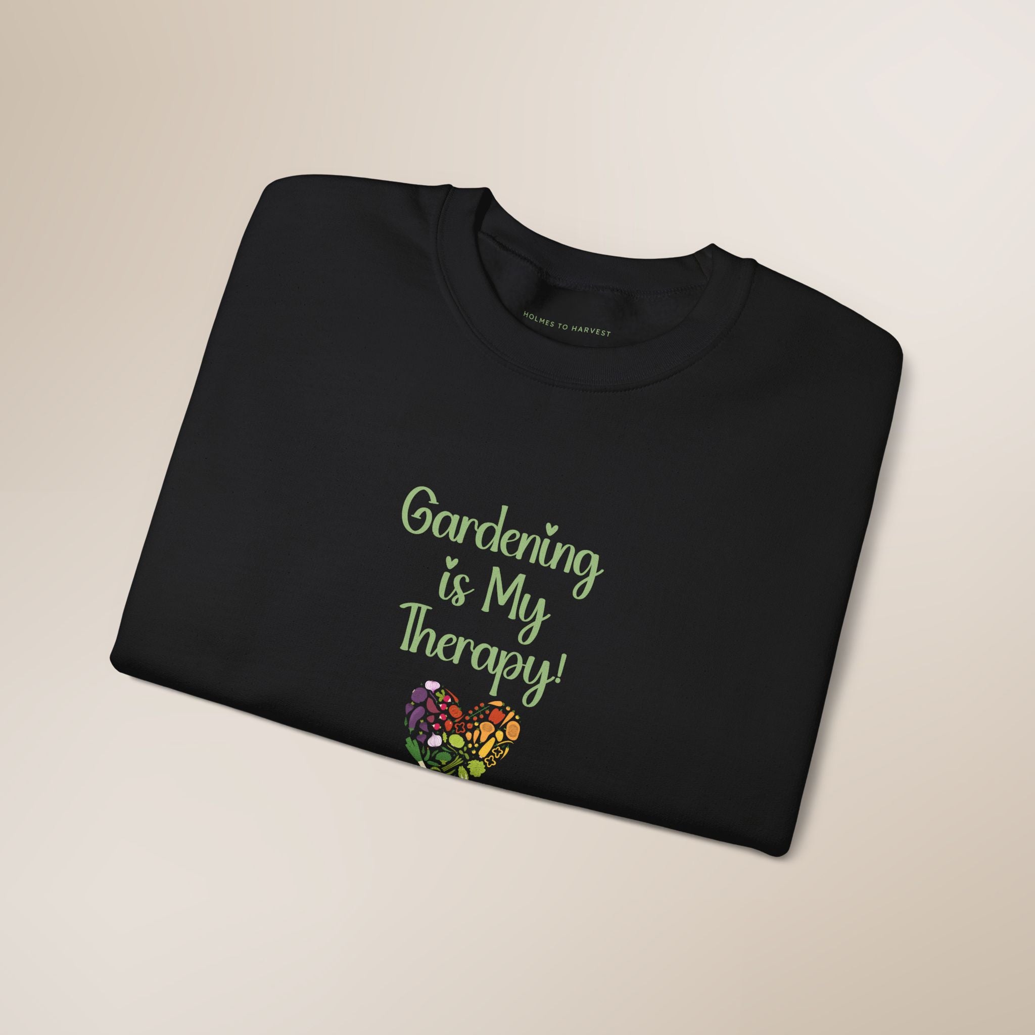 Folded black t-shirt with 'Gardening is My Therapy!' text and floral design on a beige background