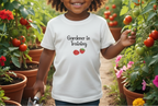 Child wearing a 'Gardener in Training' shirt in a garden with plants and tomatoes.