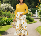 Woman in a yellow top and floral skirt holding flowers in a garden