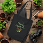 Black tote bag with 'Daddy Gardener' design on a white surface with stationery items.